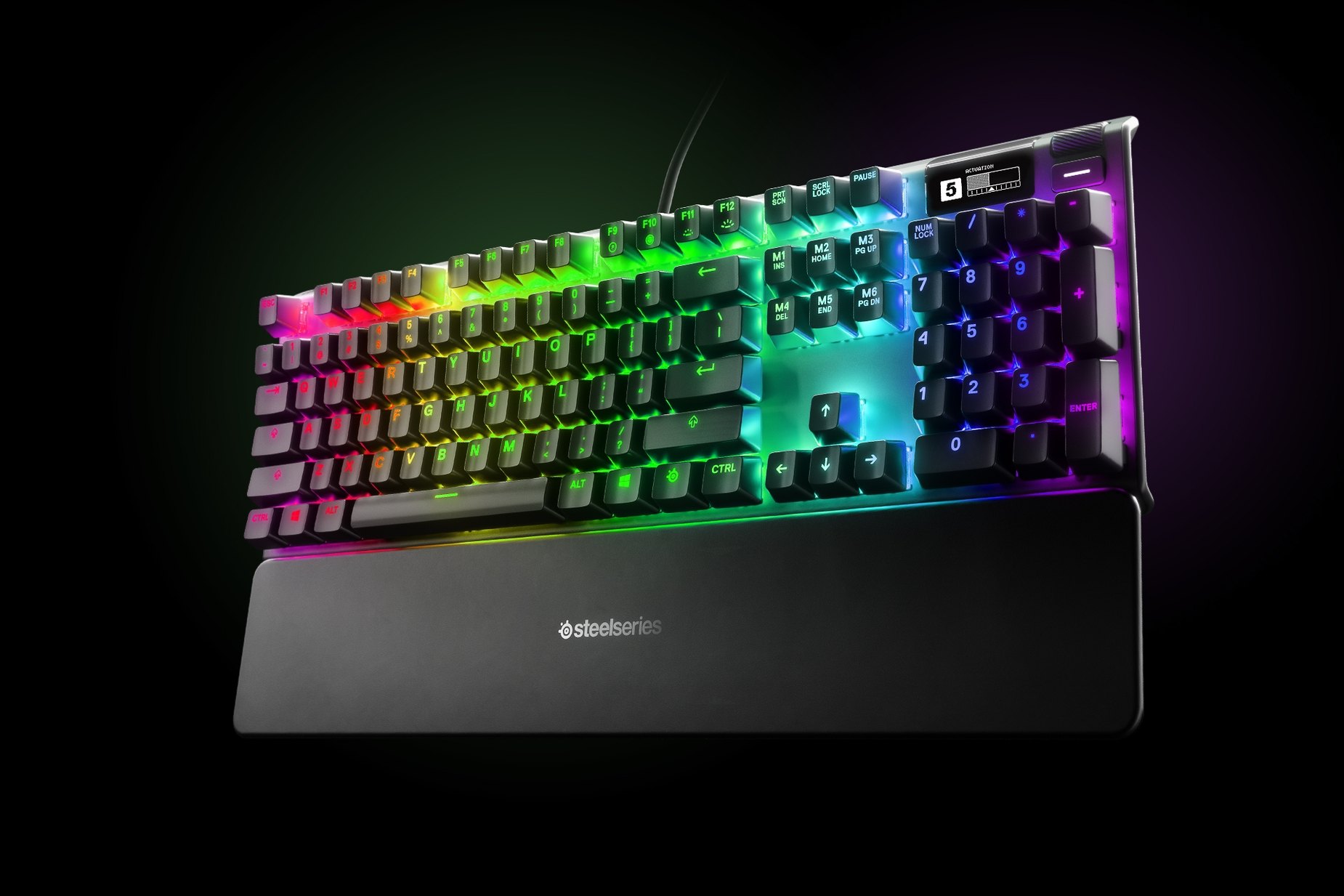 
 German - Apex Pro gaming keyboard with the illumination lit up on dark background, also shows the OLED screen and controls used to change settings, switch actuation, and adjust audio
 