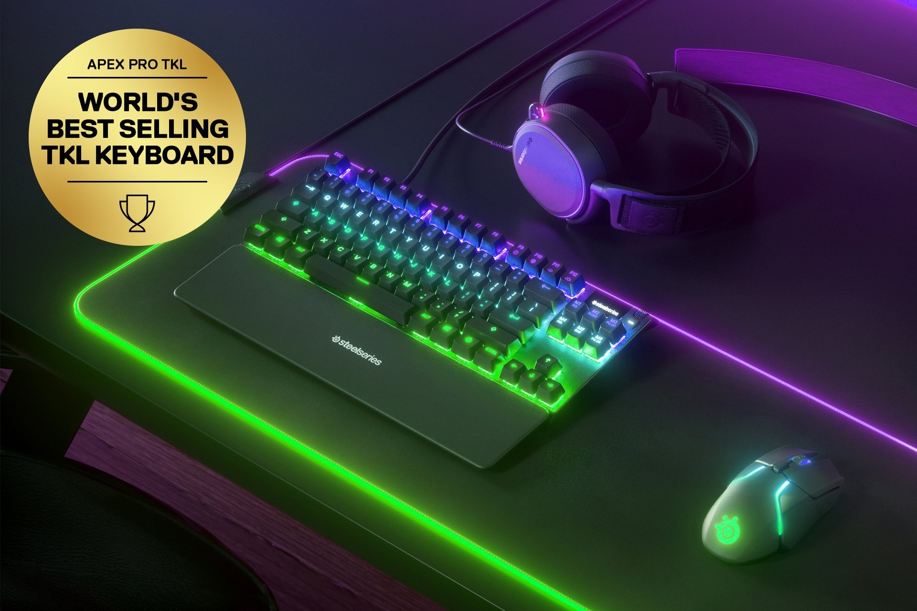
 German - Apex Pro TKL gaming keyboard on a desk with a gaming mouse, both on top of a large mousepad and a SteelSeries gaming headset next to them. Keyboard has gold award floating next to it with text "World's best selling TKL Keyboard".
 